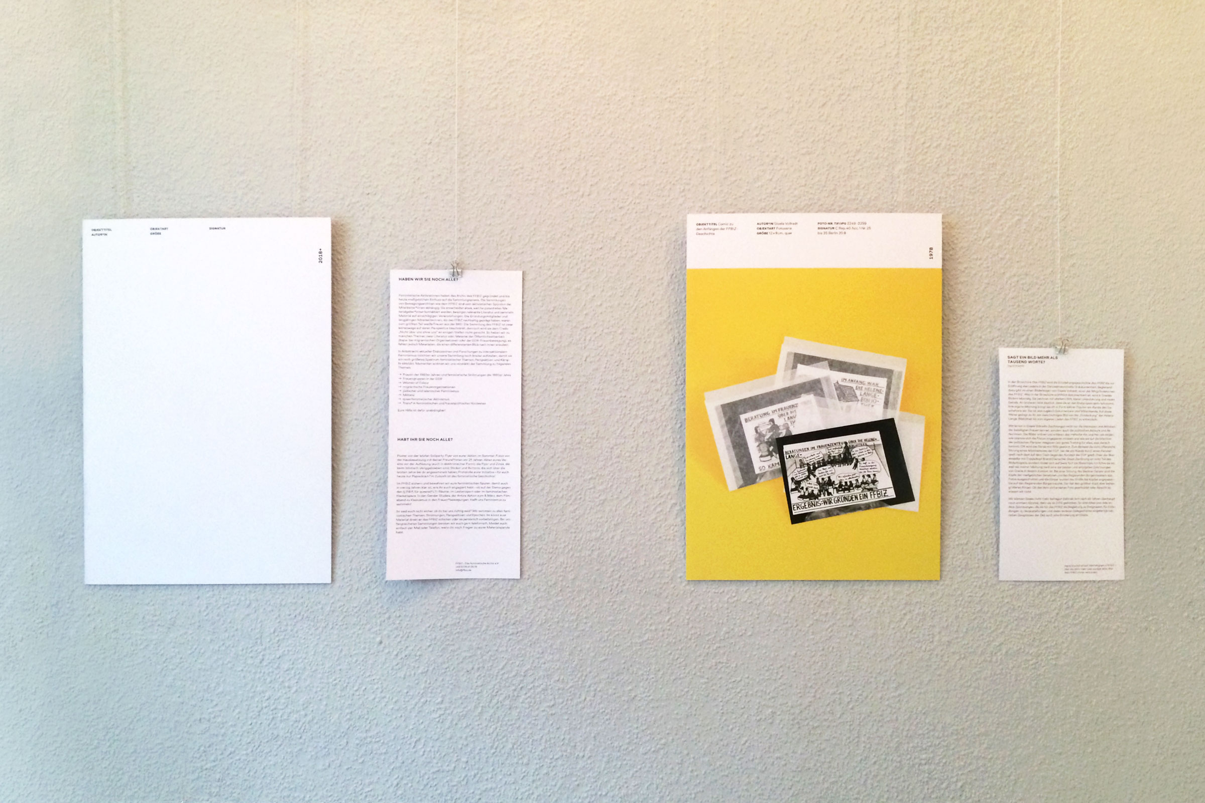 zwei hängende Ausstellungstafeln mit Infozetteln: die rechte Tafel dokumentiert in Form von Comics die FFBIZ-Geschichte; die linke Tafel ist leer und soll die Leerstellen im Archiv markieren