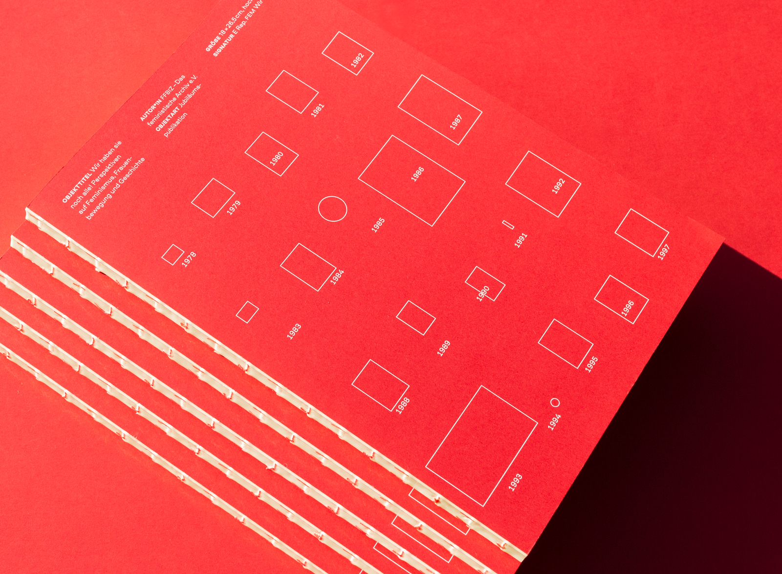 mehrere rote Ausgaben der FFBIZ Jubiläumspublikation übereinander auf rotem Hintergrund